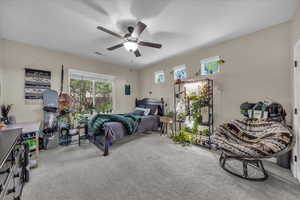 Bedroom with light carpet, multiple windows, and a ceiling fan