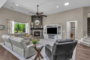 Living area featuring wood finished floors, stairs, a stone fireplace, a ceiling fan, and recessed lighting