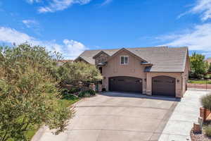 View of front facade featuring a tiled roof, stucco siding, driveway, and stone siding