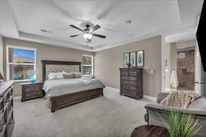 Bedroom featuring a tray ceiling, light carpet, and ceiling fan