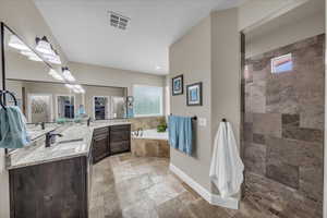 Bathroom with double vanity, a garden tub, and stone tile flooring