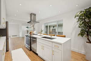 Kitchen with white cabinets, light wood finished floors, light stone countertops, island exhaust hood, and recessed lighting