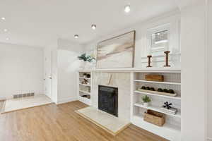 Unfurnished living room featuring a tile fireplace, light wood finished floors, and recessed lighting