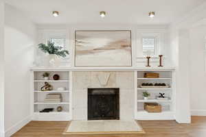 Unfurnished living room with a tile fireplace, light wood-style floors, and healthy amount of natural light