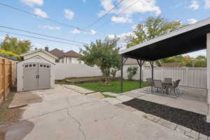 Fenced backyard with a storage shed, a patio area, and outdoor dining space