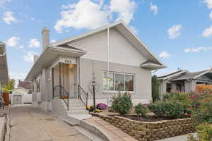 View of front of house with an outbuilding, brick siding, and a chimney