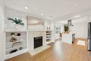 Living area featuring a premium fireplace, light wood finished floors, and recessed lighting