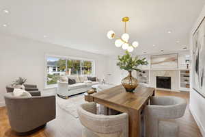 Dining space with light wood-style flooring, a premium fireplace, a chandelier, and recessed lighting