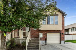 View of corner front facade with a garage, stucco, brick siding, and concrete driveway