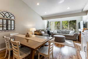 Dining area featuring laminate / wood-style flooring, recessed lighting, and high vaulted ceiling