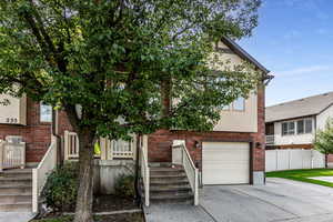 View of front of property with a garage, extra parking space, driveway, and brick siding