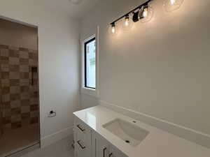 Full bathroom featuring vanity, tiled shower, and light tile patterned floors