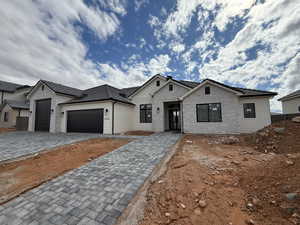 View of front of property with decorative driveway and an attached garage