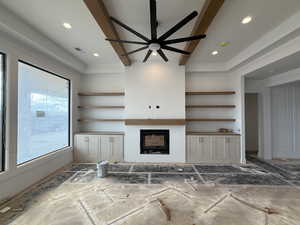 Unfurnished living room featuring beam ceiling, a glass covered fireplace, and a ceiling fan
