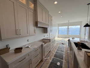 Kitchen with pendant lighting, light stone countertops, recessed lighting, black electric stovetop, and a chandelier