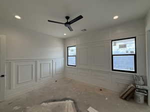 Unfurnished room featuring a decorative wall, wainscoting, ceiling fan, and recessed lighting