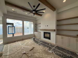 Unfurnished living room featuring beam ceiling, a glass covered fireplace, ceiling fan, built in features, and recessed lighting
