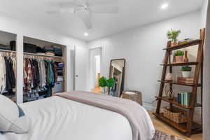 Bedroom featuring wood finished floors, recessed lighting, a ceiling fan, and two closets