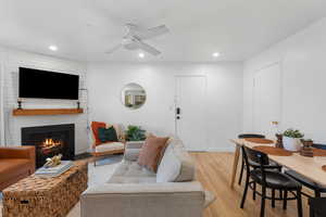 Living area featuring light wood-type flooring, recessed lighting, ceiling fan, and a fireplace