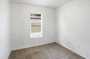 Carpeted empty room featuring baseboards
