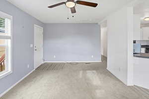 Unfurnished living room featuring light carpet and ceiling fan