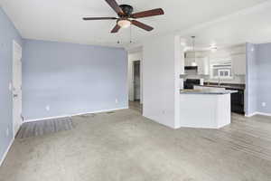Kitchen featuring white cabinetry, a ceiling fan, dark countertops, pendant lighting, and black appliances