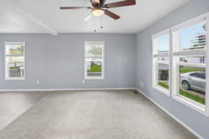 Unfurnished room with healthy amount of natural light, light carpet, beam ceiling, and ceiling fan