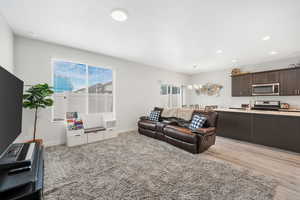 Living room featuring light wood-style flooring, recessed lighting, and a chandelier
