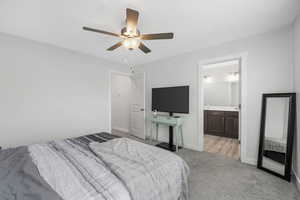 Bedroom with light colored carpet, a ceiling fan, and ensuite bathroom