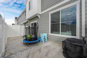 Fenced backyard with a trampoline and a patio area