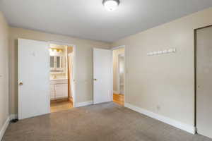 Unfurnished bedroom with light colored carpet and baseboards