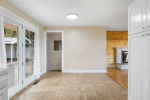 Unfurnished dining area featuring a fireplace, light tile patterned floors, and wood walls