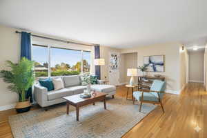 Digitally staged. Living area with light wood finished floors