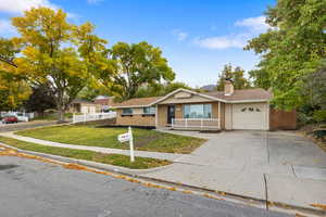 Ranch-style house with brick siding, an attached garage, concrete driveway, and a chimney