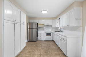 Kitchen with tile counters, white appliances, white cabinets, and light tile patterned floors