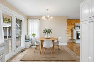 Dining room with a brick fireplace, a chandelier, light tile patterned floors, and wooden walls