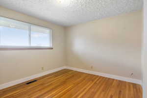 Unfurnished room featuring light wood-style flooring and a textured ceiling