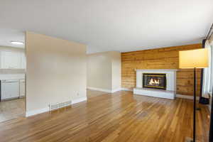 Unfurnished living room featuring wood walls, light wood-style flooring, and a fireplace