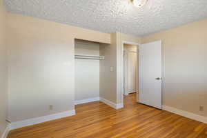 Unfurnished bedroom featuring light wood-style floors, a closet, and a textured ceiling