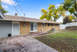 Back of house featuring a patio, brick siding, a shingled roof, and a chimney