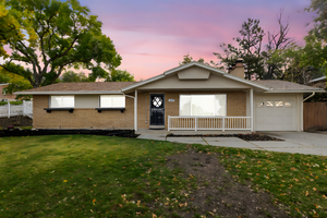 Ranch-style home featuring an attached garage, brick siding, and a chimney