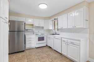 Kitchen with tile counters, white appliances, decorative backsplash, white cabinetry, and light tile patterned flooring