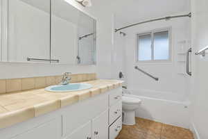 Bathroom with shower / tub combination, vanity, and light tile patterned flooring