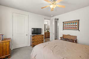 Bedroom with light carpet, ceiling fan, and ensuite bathroom
