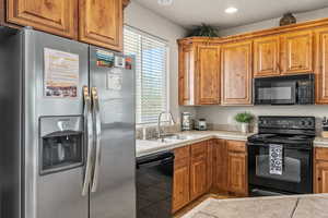 Kitchen with black appliances, brown cabinets, and recessed lighting