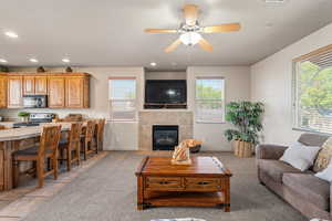 Living area featuring light colored carpet, ceiling fan, recessed lighting, and a fireplace