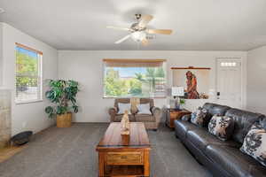 Carpeted living area featuring plenty of natural light and ceiling fan