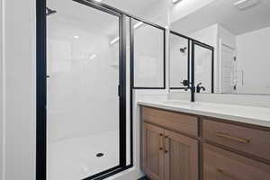 Full bath with vanity, a shower stall, and a textured ceiling
