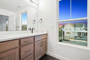 Bathroom featuring double vanity, a textured ceiling, and dark tile patterned floors