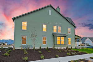 View of front of home featuring stucco siding, a chimney, and a shingled roof